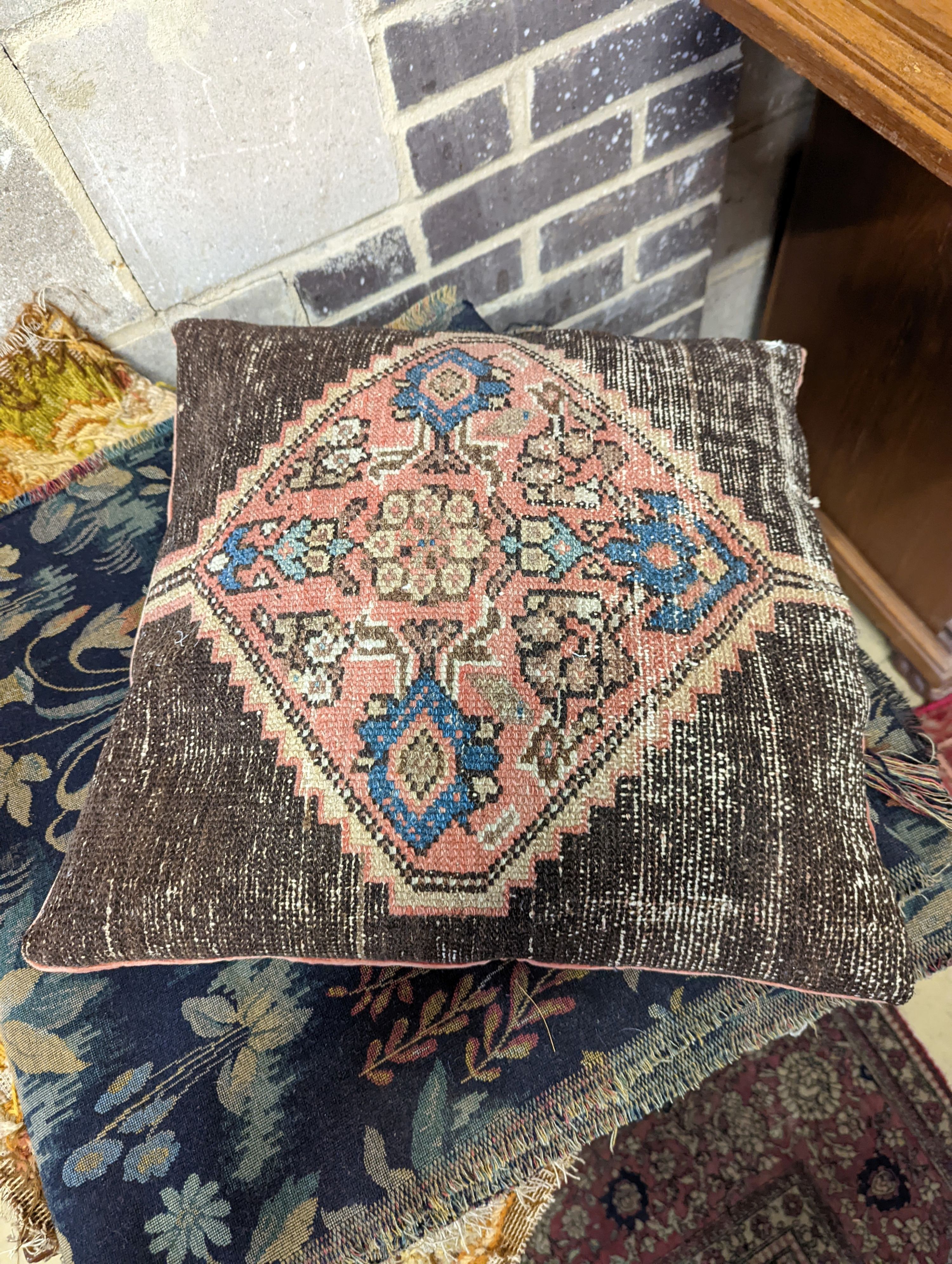 A length of machine tapestry fabric with flowers on a black ground, 420 x 52cm together with a Caucasian rug faced cushion and an antique English needlework panel with stylised scrolls 175 x 67cm